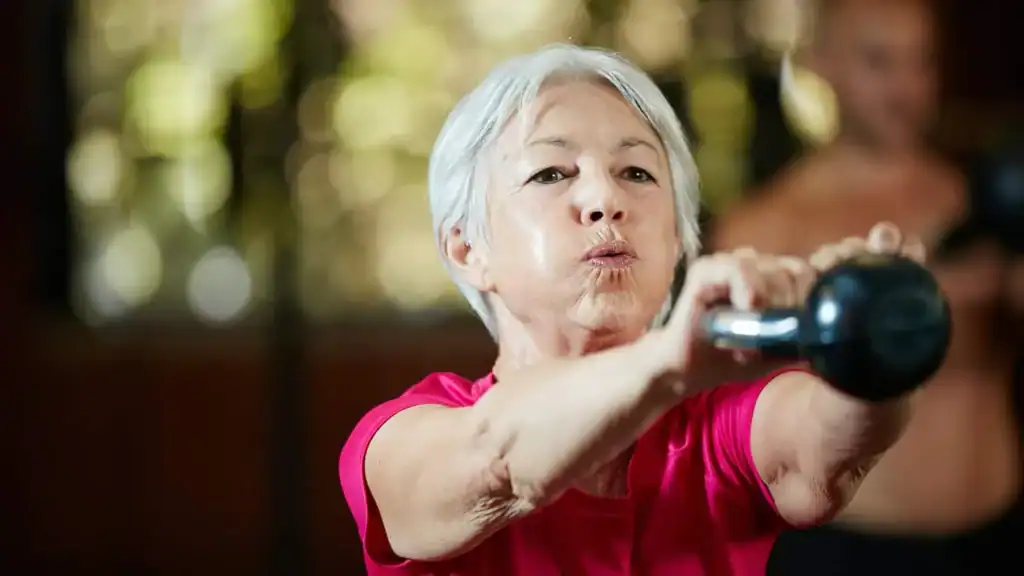 Older woman doing weight training Aldridge to help her strength and longevity 