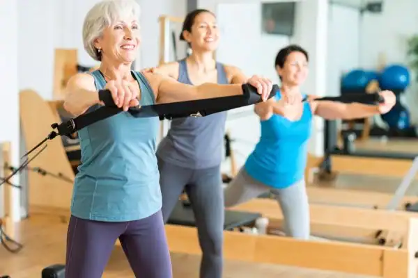 Toning Arms After 60: Empowering Womens Fitness Through Effective Weight Training 2 older woman doing weight training Aldridge and resistance in the gym to tone upper arms