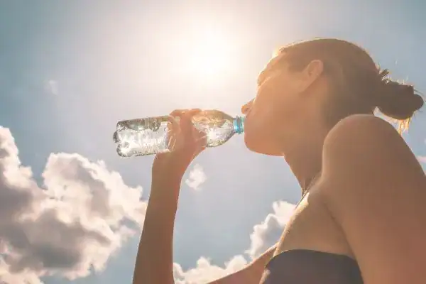 Hydration: The Secret Ingredient for a Toned Stomach and Enhanced Fitness 3 Image of woman drinking water to hydrate Aldridge after run.