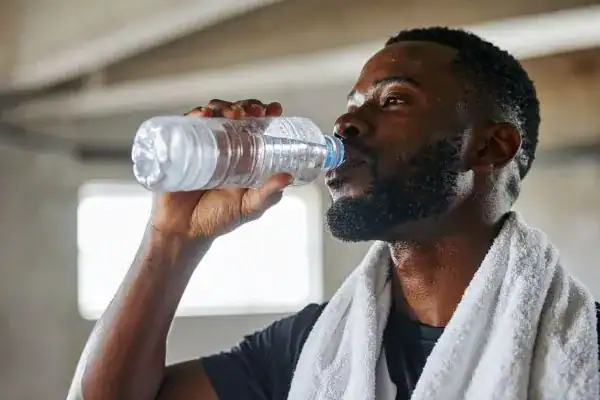 Image of man drinking water to improve hydration Aldridge after work out.